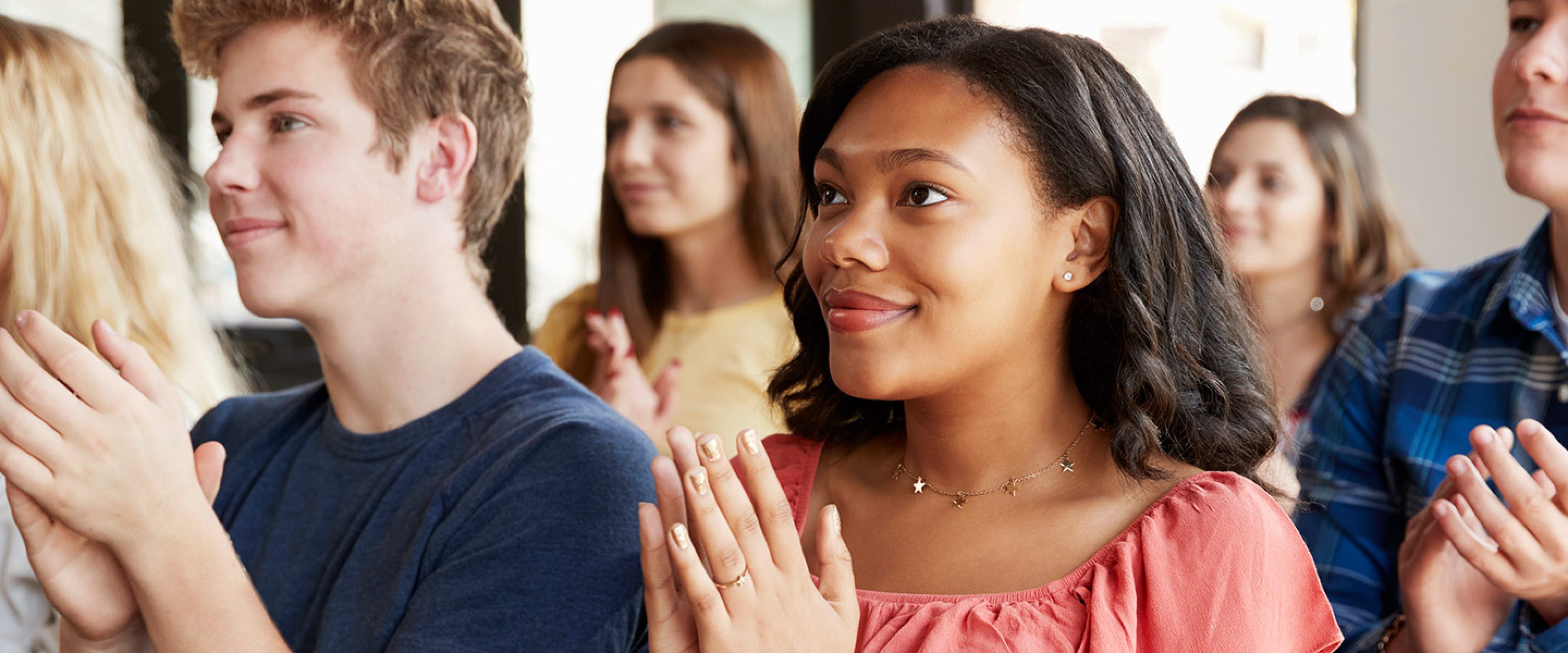 Group of students claps while listening to lecture