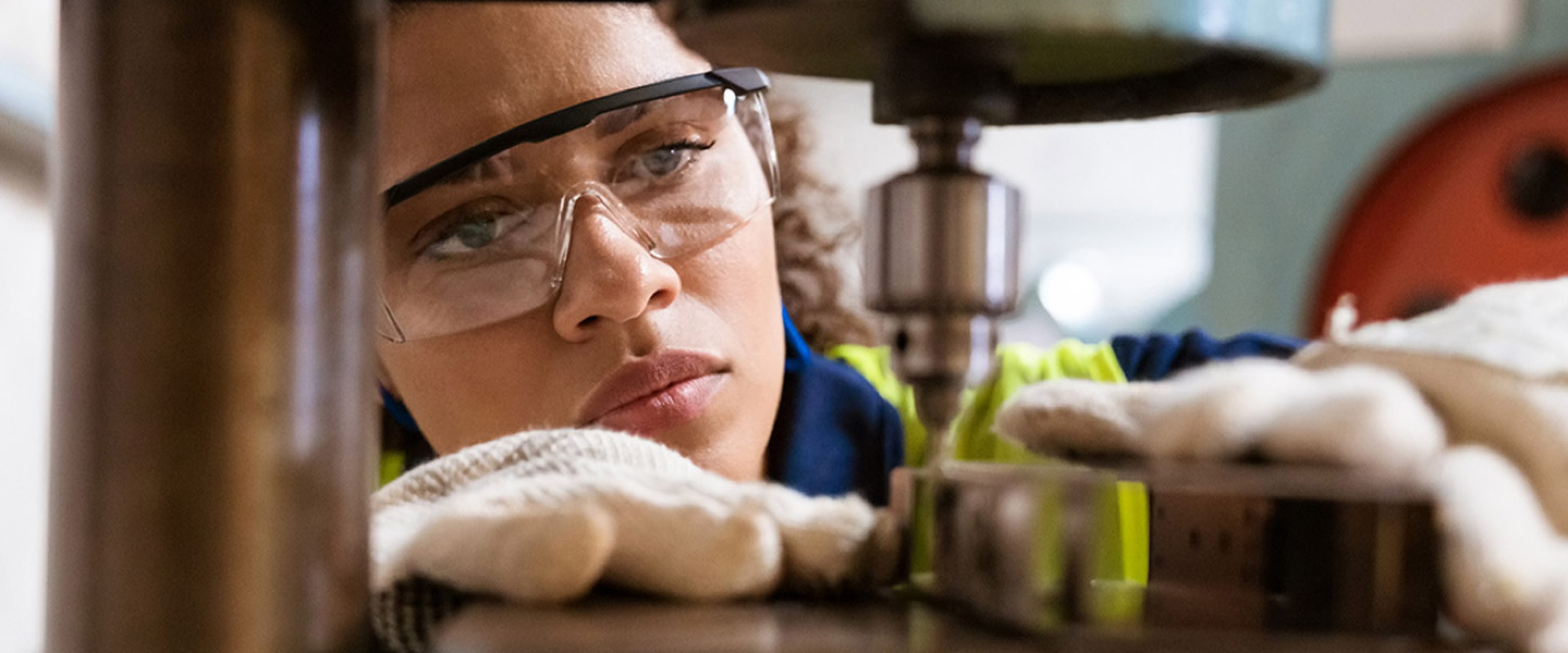 Closeup of female worker wearing safety glasses and working on a machine