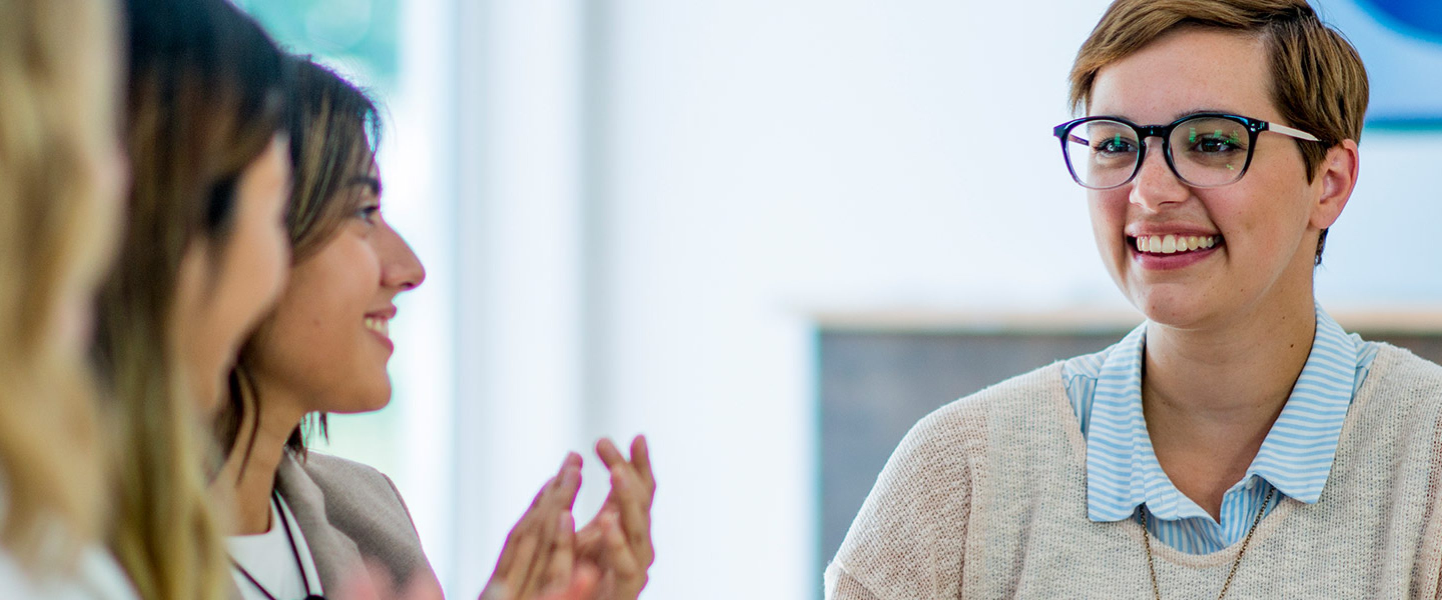 Young female professional with short hair and glasses meets with other female colleagues