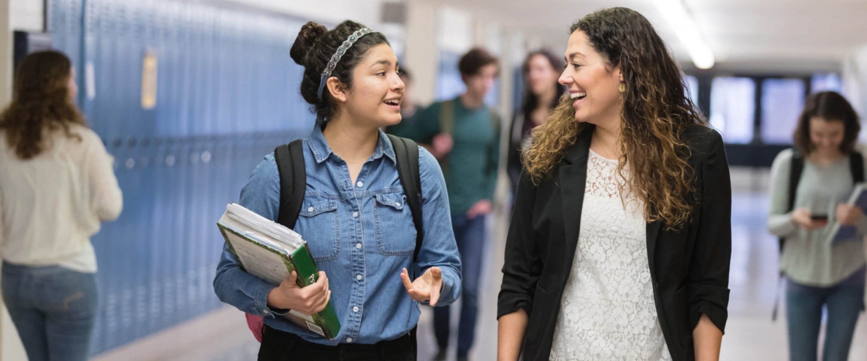 Two high school students walk down a hallway